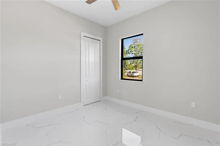 Unfurnished bedroom featuring light marble finish floors, a closet, and ceiling fan