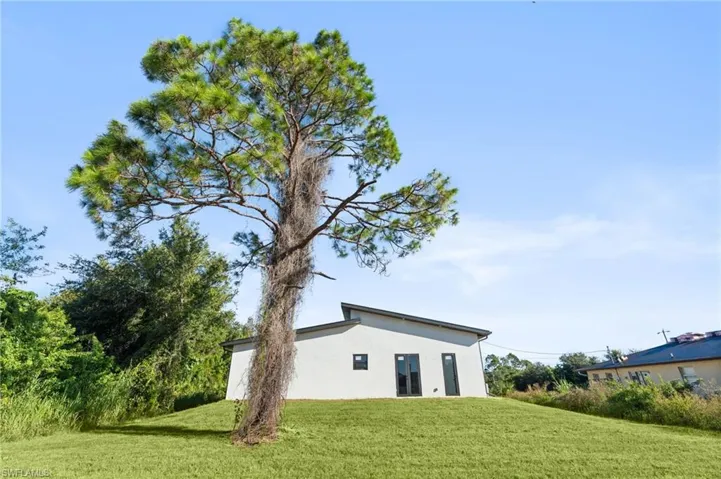 Back of house with a yard and stucco siding