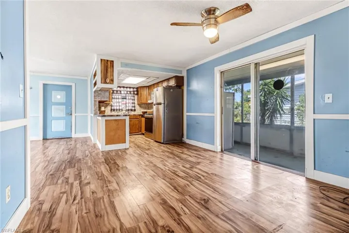 Kitchen featuring ceiling fan, crown molding, tasteful backsplash, stainless steel fridge, and hardwood / wood-style flooring