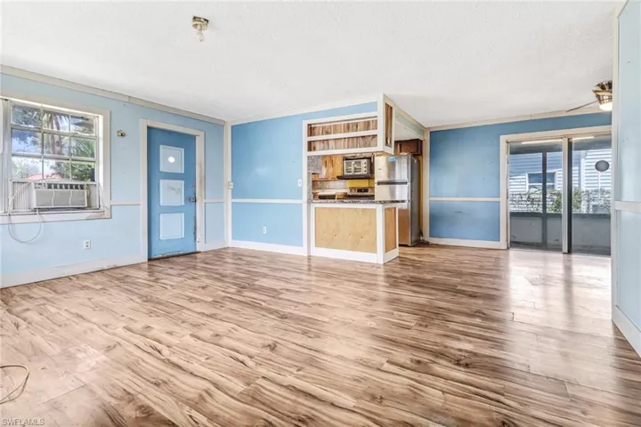 Unfurnished living room featuring crown molding, hardwood / wood-style flooring, and a textured ceiling