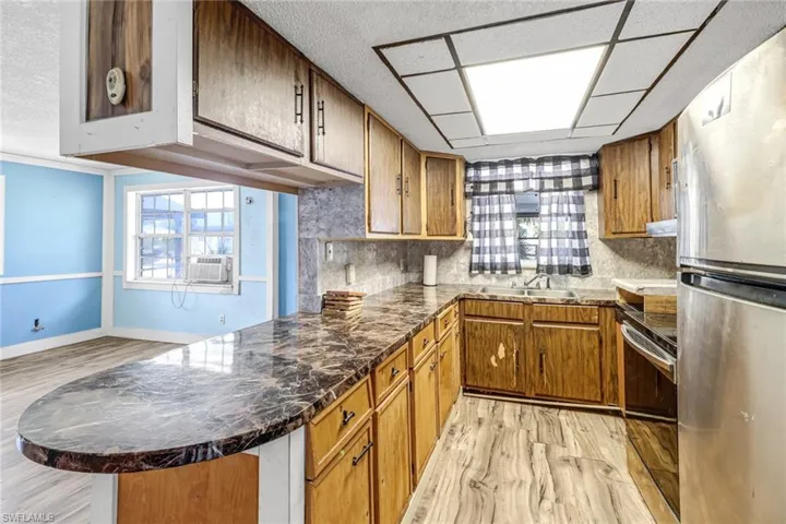 Kitchen featuring stainless steel appliances, kitchen peninsula, tasteful backsplash, and light wood-type flooring