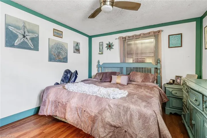 Bedroom with wood-type flooring, ceiling fan, and a textured ceiling