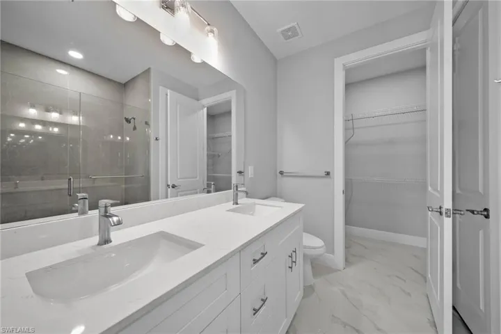 Bathroom featuring walk in shower, vanity, and toilet