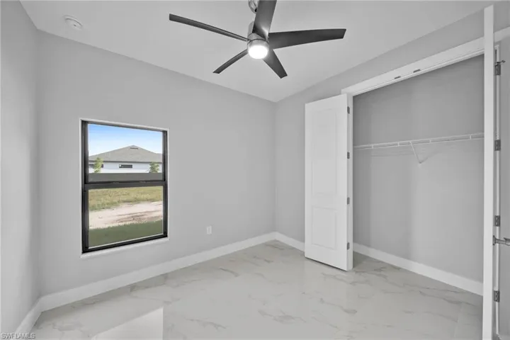 Unfurnished bedroom with ceiling fan and a closet