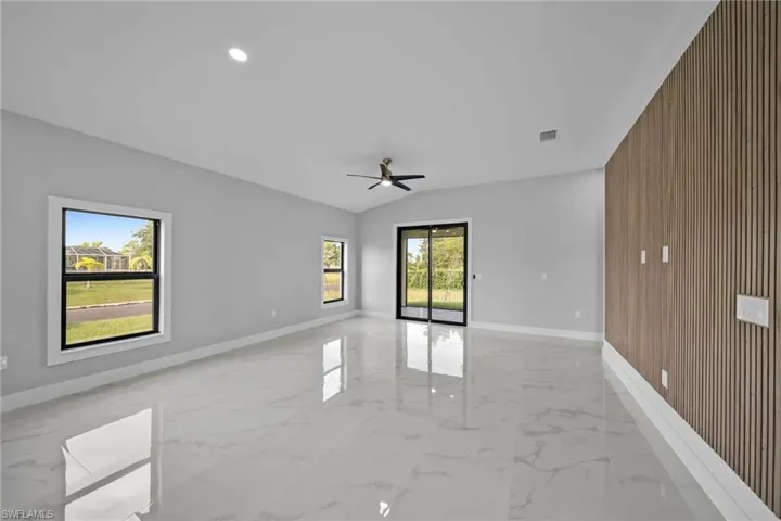 Spare room with wooden walls, vaulted ceiling, and ceiling fan