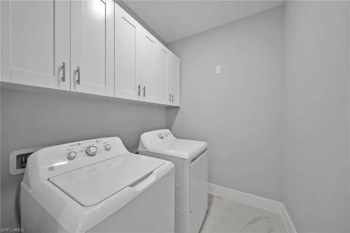 Washroom featuring washing machine and dryer and cabinets