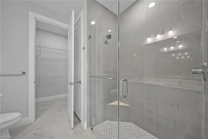 Bathroom featuring toilet and a shower with shower door