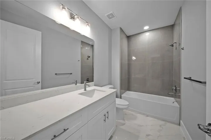 Full bathroom with tiled shower / bath combo, vanity, and toilet