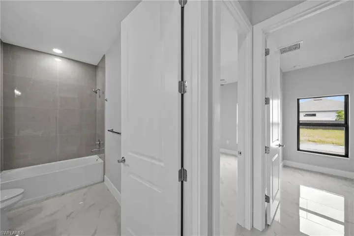 Bathroom featuring tiled shower / bath combo and toilet