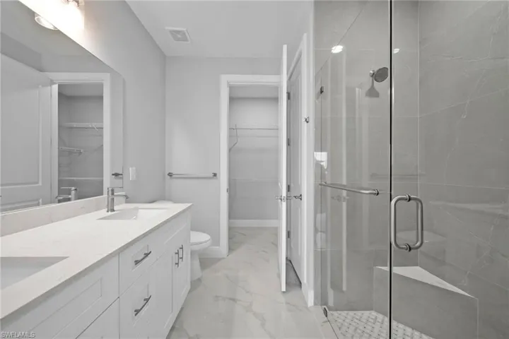 Bathroom featuring vanity, a shower with shower door, and toilet