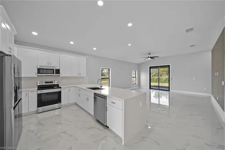 Kitchen featuring sink, white cabinets, kitchen peninsula, stainless steel appliances, and ceiling fan