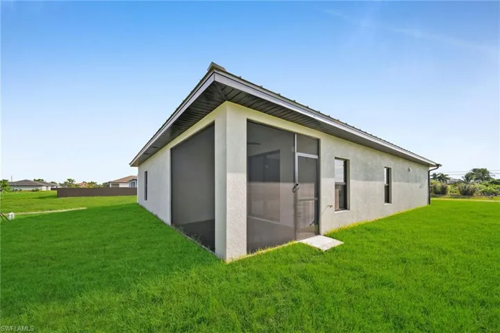 View of outbuilding with a lawn and a sunroom