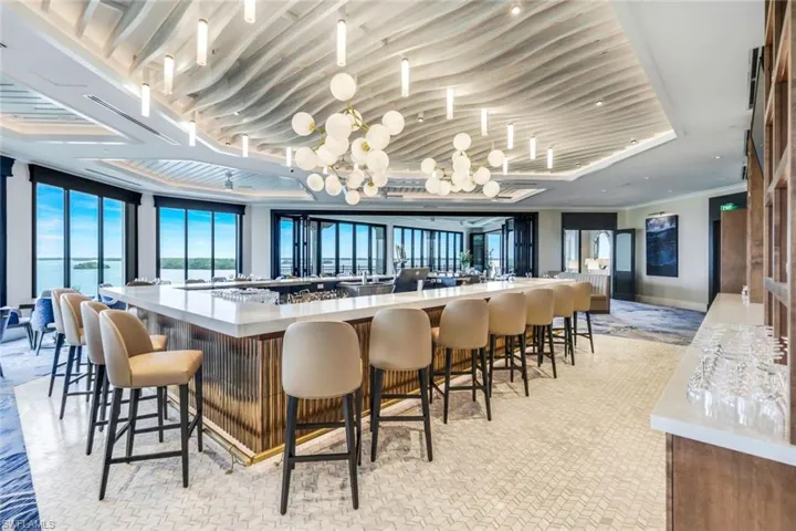 Bar with crown molding, a water view, light colored carpet, and a raised ceiling