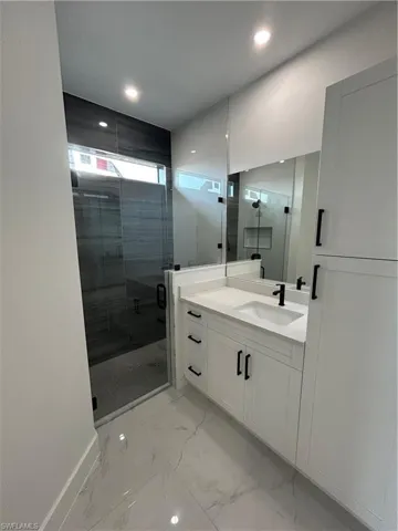 Full bathroom featuring baseboards, marble finish floor, recessed lighting, vanity, and a stall shower