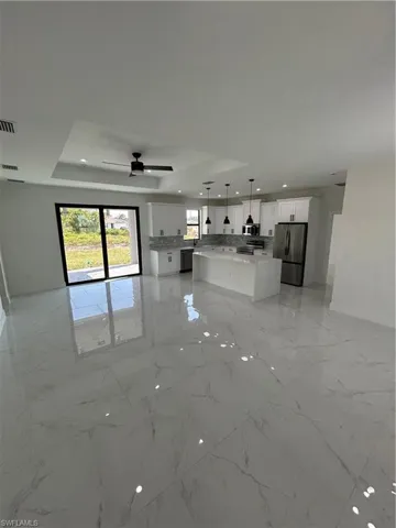 Unfurnished living room featuring a tray ceiling, recessed lighting, marble finish floor, visible vents, and ceiling fan
