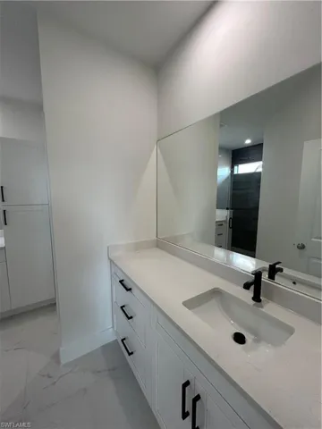 Bathroom with marble finish floor, vanity, and baseboards