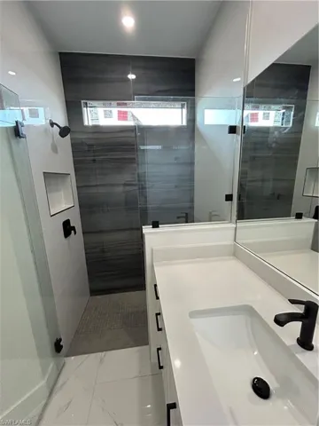 Bathroom with marble finish floor, a stall shower, and vanity
