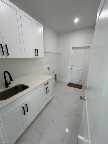 Laundry area featuring a sink, washer hookup, electric dryer hookup, marble finish floor, and cabinet space