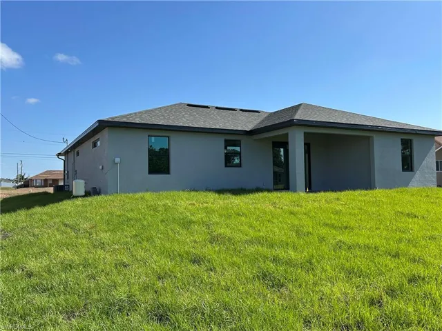 Back of house with stucco siding and a yard
