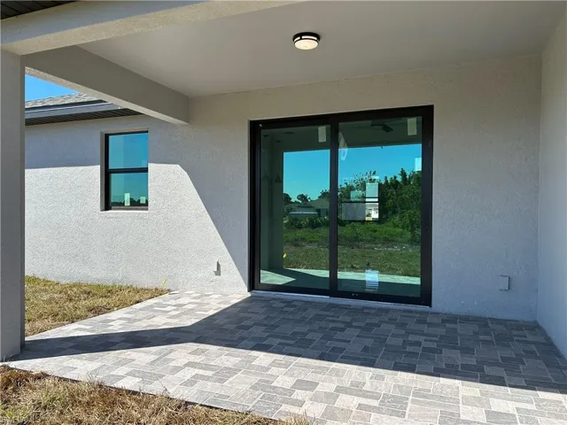 Entrance to property with stucco siding and a patio