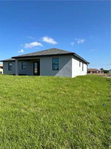 Back of house featuring stucco siding and a yard