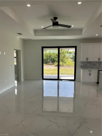 Empty room featuring marble finish floor, a raised ceiling, ceiling fan, and visible vents