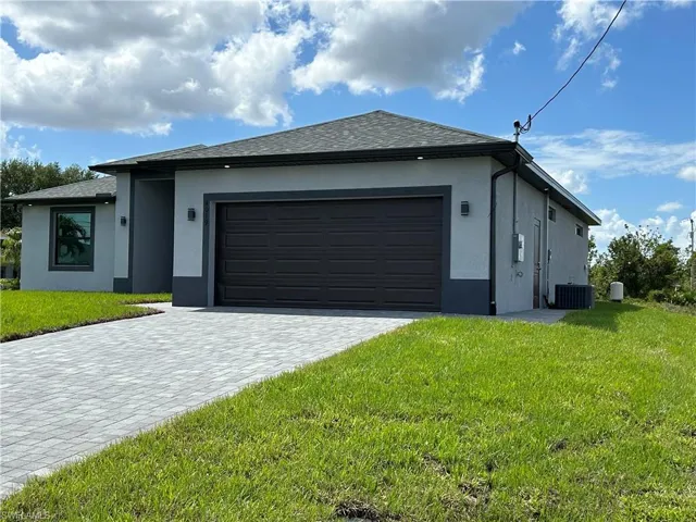 View of front of property featuring decorative driveway, central AC unit, a garage, and stucco siding