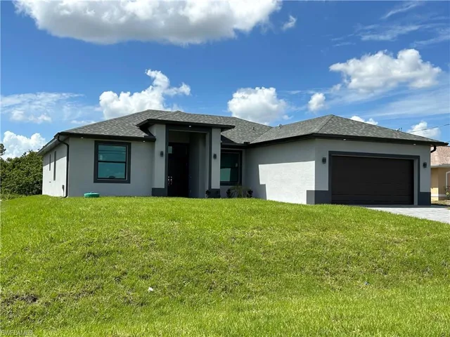 Prairie-style home featuring a front lawn, roof with shingles, stucco siding, an attached garage, and driveway
