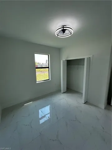 Unfurnished bedroom with baseboards, marble finish floor, and a closet