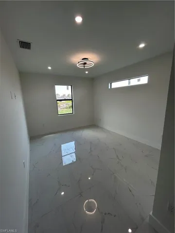 Unfurnished room with marble finish floor, baseboards, visible vents, and recessed lighting