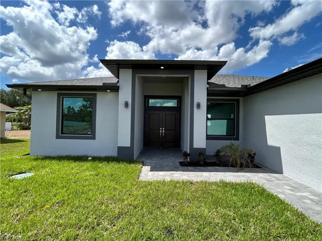 Doorway to property with a lawn and stucco siding