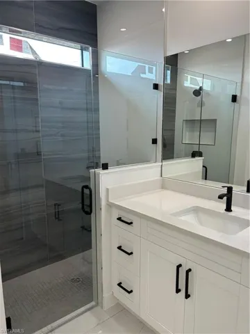 Full bath featuring marble finish floor, vanity, and a shower stall