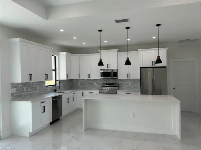 Kitchen with visible vents, marble finish floor, appliances with stainless steel finishes, a sink, and a center island