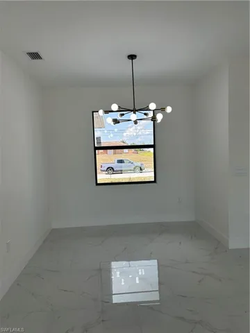 Unfurnished room with marble finish floor, baseboards, a chandelier, and visible vents