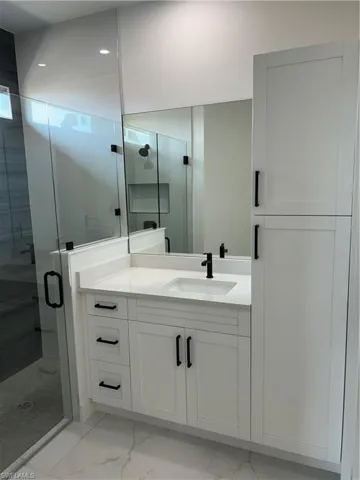 Bathroom featuring marble finish floor, recessed lighting, vanity, and a shower stall