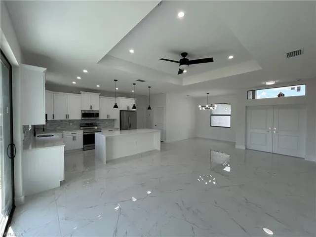 Kitchen with open floor plan, a tray ceiling, stainless steel appliances, marble finish floor, and visible vents