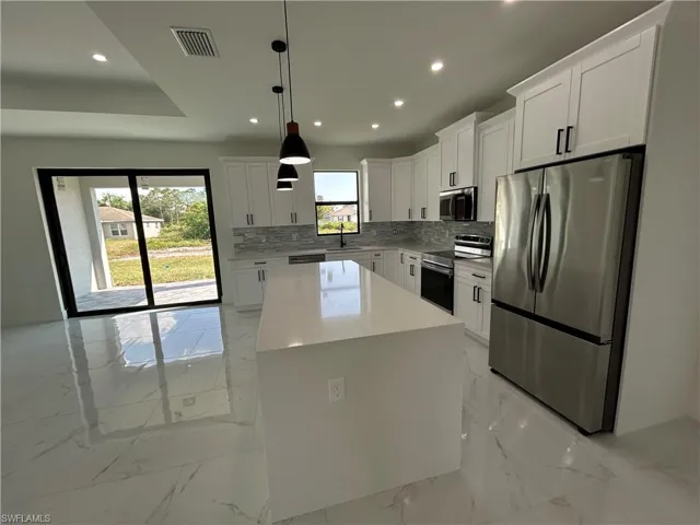 Kitchen featuring marble finish floor, stainless steel appliances, a healthy amount of sunlight, and visible vents