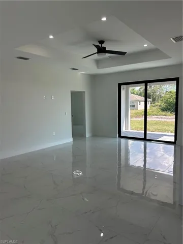 Spare room with a tray ceiling, marble finish floor, baseboards, visible vents, and recessed lighting
