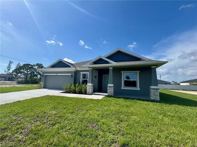 Craftsman house with driveway, a front yard, stucco siding, a garage, and covered porch