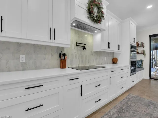 Kitchen featuring white cabinetry, decorative backsplash, recessed lighting, light tile patterned floors, and ornamental molding