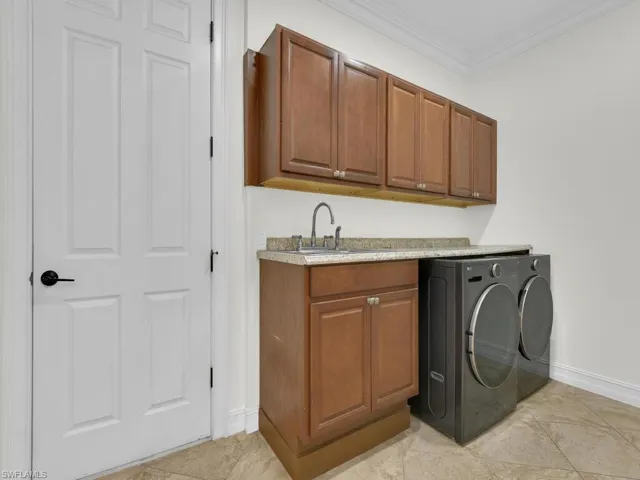 Laundry room featuring ornamental molding, cabinet space, separate washer and dryer, and light tile patterned floors