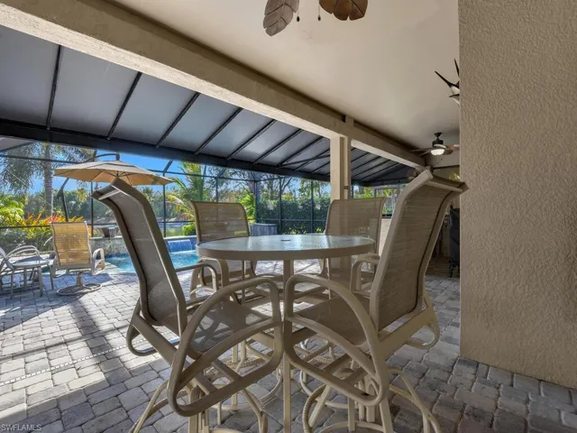 View of patio / terrace featuring outdoor dining area, an outdoor pool, a ceiling fan, and glass enclosure