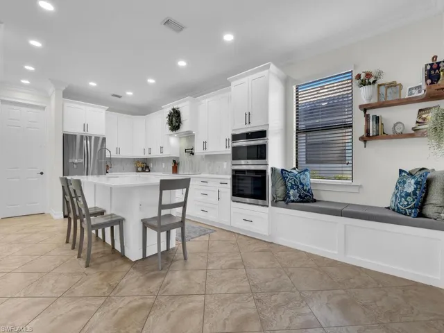 Kitchen featuring ornamental molding, white cabinets, a center island, a breakfast bar, and stainless steel appliances