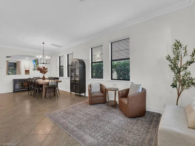 Tiled living room with ornamental molding and hanging lights