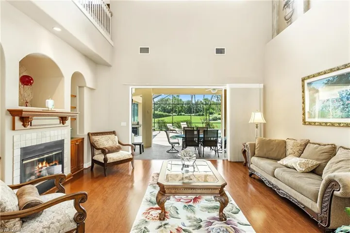 Two-story living area featuring wood-finish flooring and a fireplace with a tiled surround and wood mantel