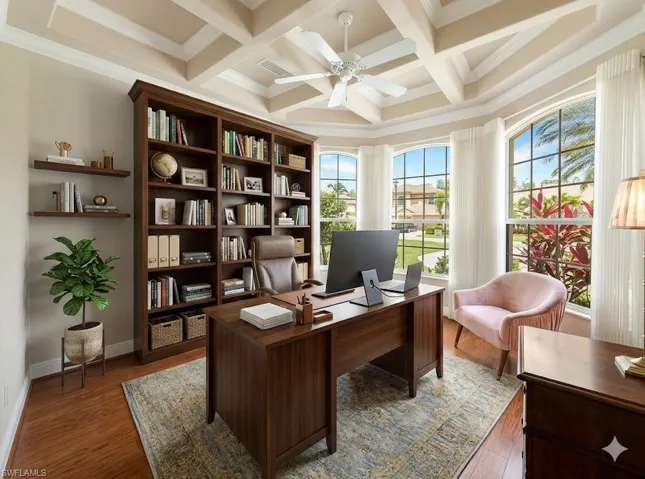 Virtually Staged Den Coffered ceiling featuring a ceiling fan, bay window with arched transoms, built-in shelving, wood-finish flooring, and natural light