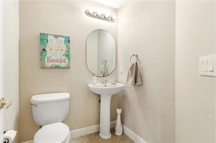 Half Bathroom on first floor with Pedestal sink with an oval mirror and a five-bulb vanity light fixture