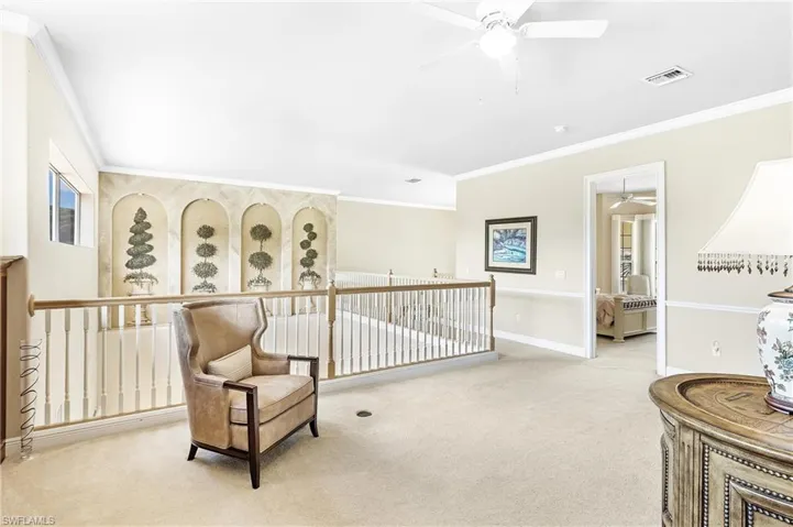 Expansive loft area featuring neutral carpeting, white baluster railings with a wood-finish handrail, and a decorative wall with arched alcoves