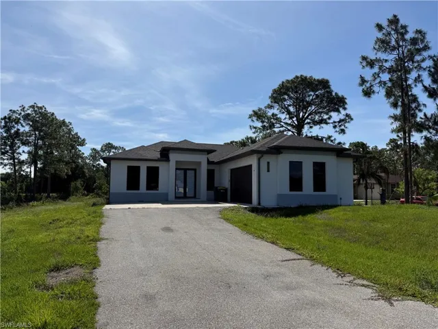 Contemporary stucco exterior with a dark shingle roof, double-door entry, attached two-car garage, and a paved driveway