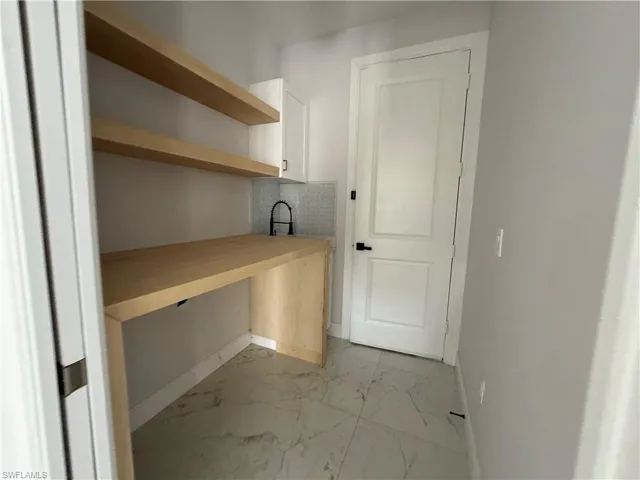 Integrated workstation with blonde wood-finish countertop, coordinating floating shelves, and a white subway tile backsplash